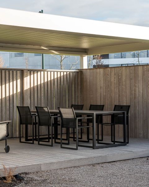 Terrasoverkapping met houten shutter en vaste zijwand in hout gecombineerd