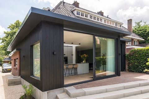 Moderne aanbouw in zwart hout bij klassieke woning Moderne aanbouw in zwart hout bij klassieke woning