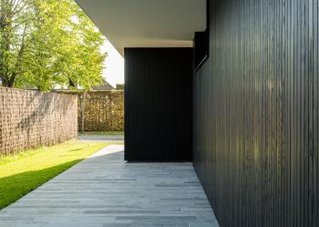 Zwarte houten gevelbekleding in contrast met natuursteen terrastegels