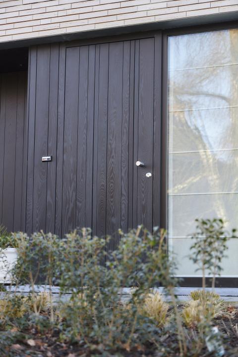 Zwarte houten gevelbekleding met ingewerkte voordeur in HOTwood essen