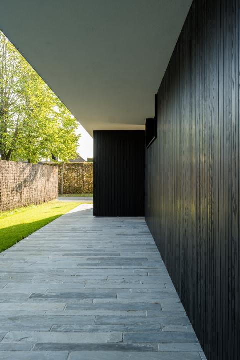 Zwarte houten gevelbekleding in contrast met natuursteen terrastegels
