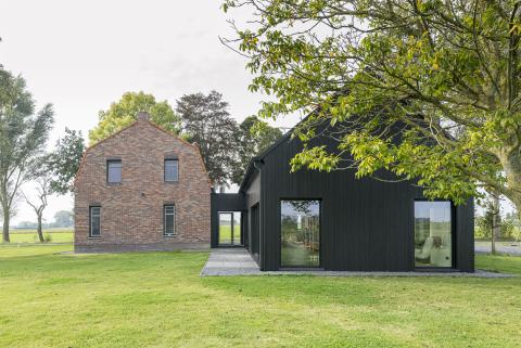 Houten aanbouw woonboerderij met zwart houten gevelbekleding in wisselende breedtes