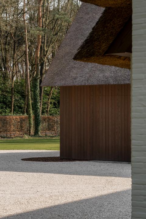 Houten gevelbekleding in Ipé kleur bij witte villa met rietdak