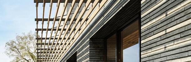 Houten zonneluifel met vaste lamellen aan gevel woning