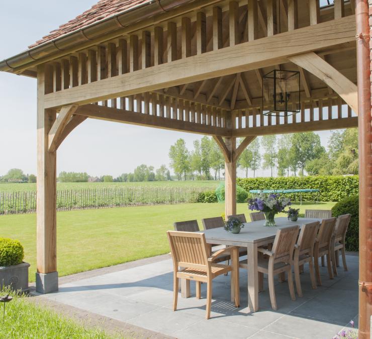 Gezellige buiten zitplaats met zicht op tuin onder landelijkse terrasoverkapping