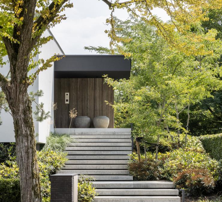 Ingang gerenoveerde moderne villa met voordeur in essen hout afwerking