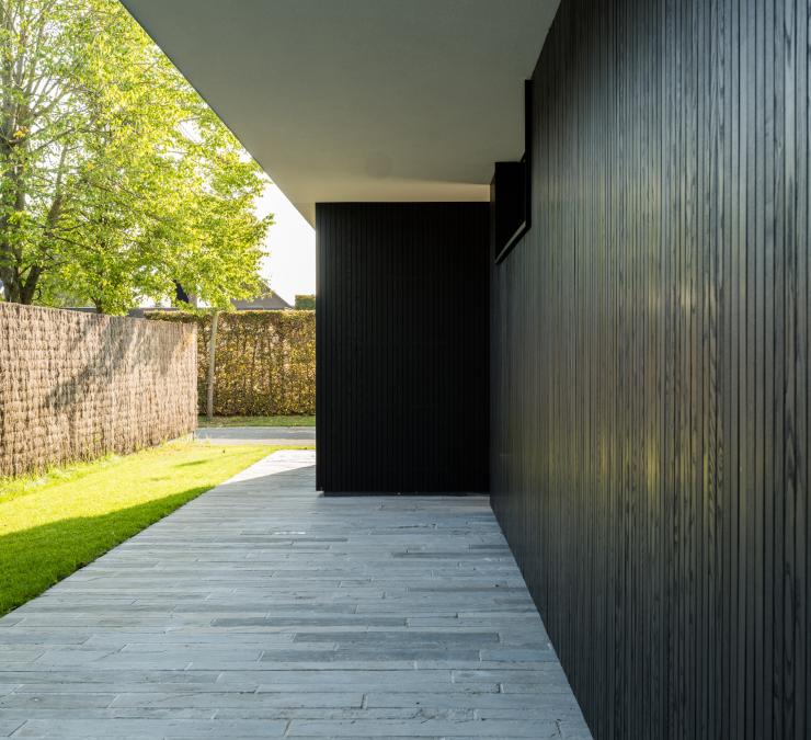 Buitenkant gevelbekleding met zwarte houten profielen met ingewerkt raam. 
