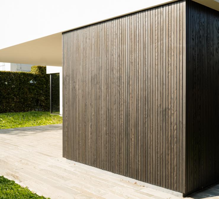 Gevelbekleding met zwarte geoliede essen hout in zonlicht