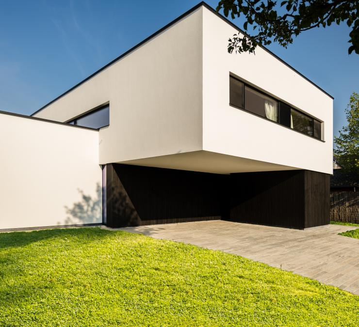 Witte strakke villa bouw met afwerking aan oprit met zwarte houten profielen