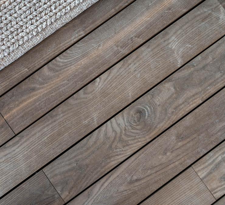 Houten terras met naadloos bevestigde bolle terrasplanken in thermisch essen