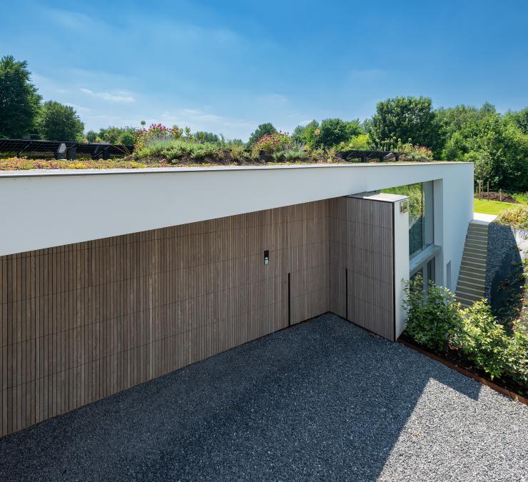 The sectional door and the pivot entry door in thermo ash blend harmoniously with the white walls of the house