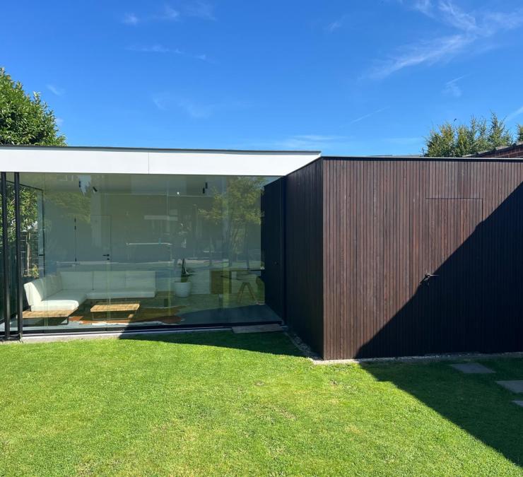 Gartenhaus neben der Terrassenüberdachung ausgeführt in HOTwood Esche Fine Line QC Bison Brown