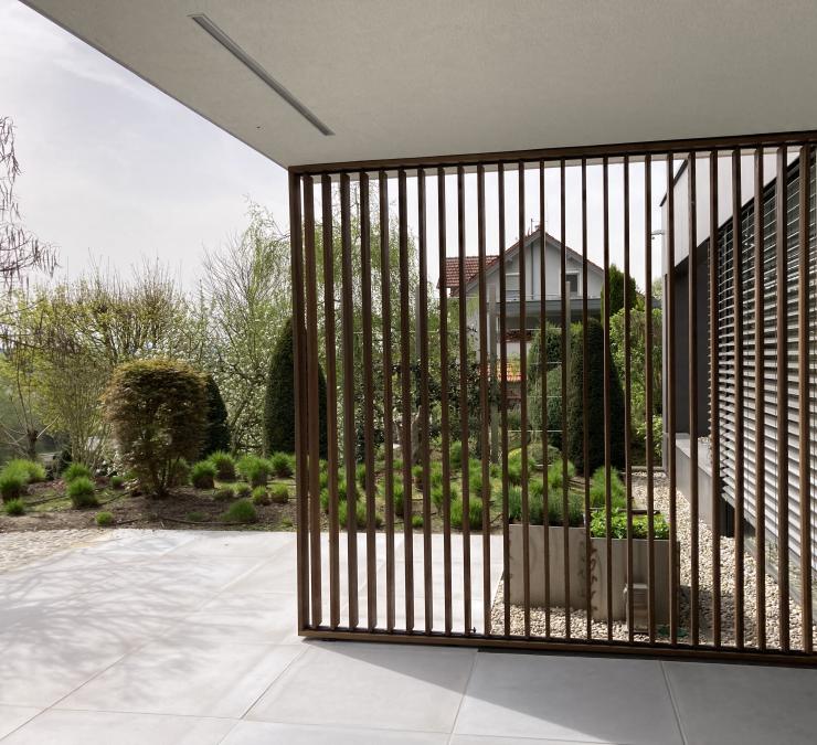 Houten shutter met open lamellen biedt doorkijk op terras woning