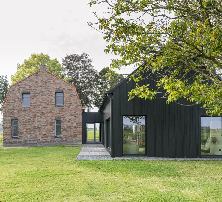 Houten aanbouw woonboerderij met zwart houten gevelbekleding in wisselende breedtes