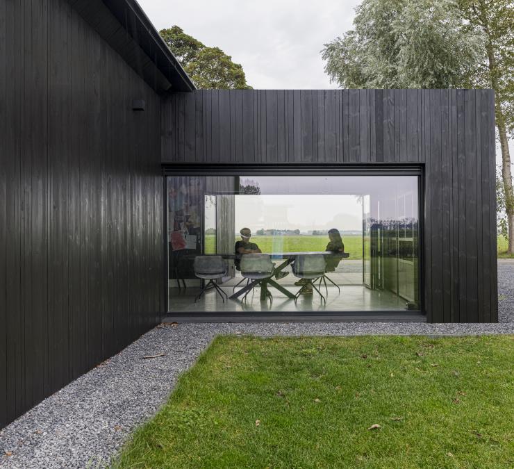 Houten aanbouw met grote ramen biedt panoramisch zicht op weids landschap