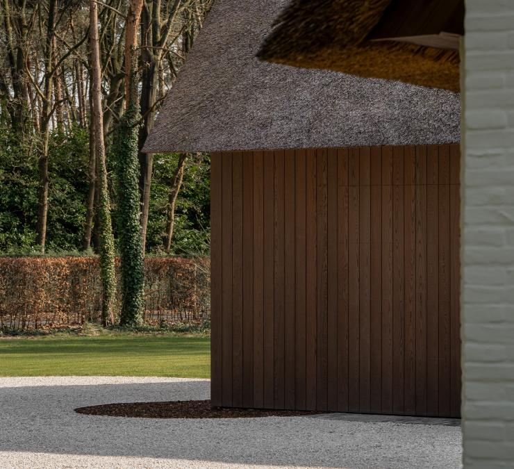 Houten gevelbekleding in Ipé kleur bij witte villa met rietdak