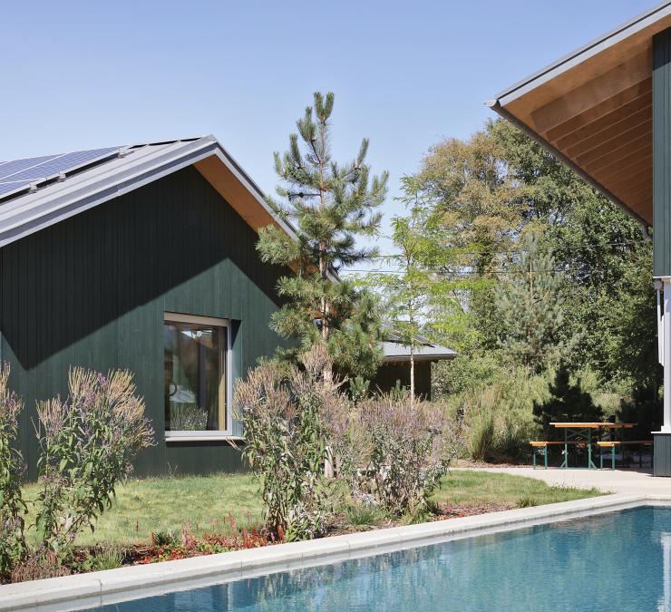 The contemporary finish of a façade in a blue-green Emerald stain blends perfectly with the landscaped surroundings