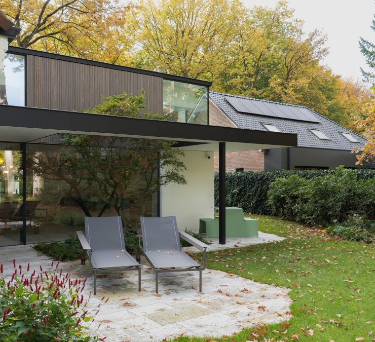 Moderne villa met grote glaspartijen en houten gevelbekleding op bovenverdieping
